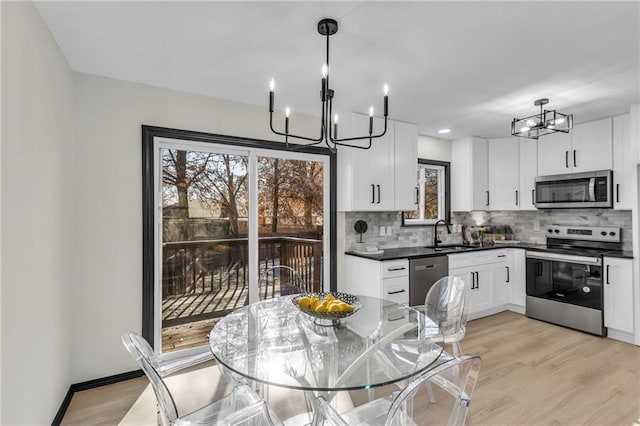 kitchen featuring hanging light fixtures, stainless steel appliances, tasteful backsplash, light hardwood / wood-style floors, and white cabinets