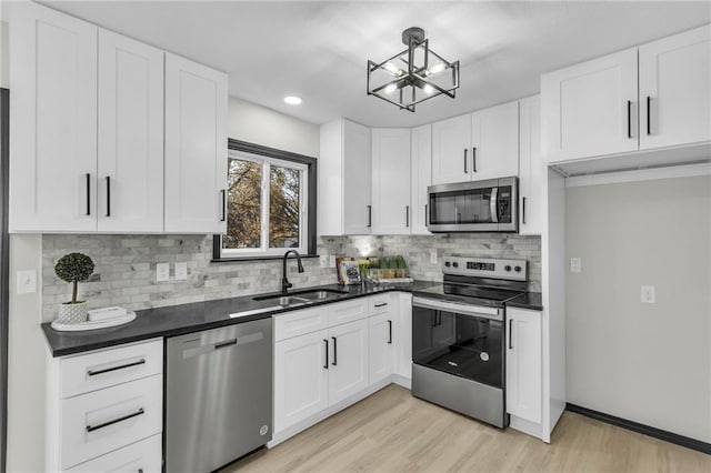 kitchen featuring decorative backsplash, stainless steel appliances, sink, white cabinets, and light hardwood / wood-style floors