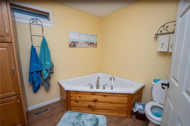 bathroom with a bathing tub, hardwood / wood-style floors, and toilet