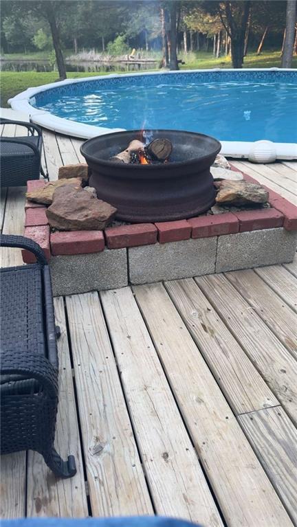 view of pool with an outdoor fire pit and a deck