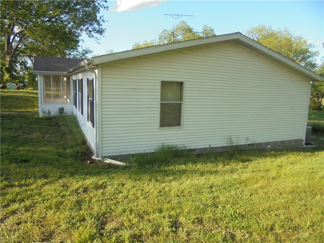 view of home's exterior with a sunroom and a lawn