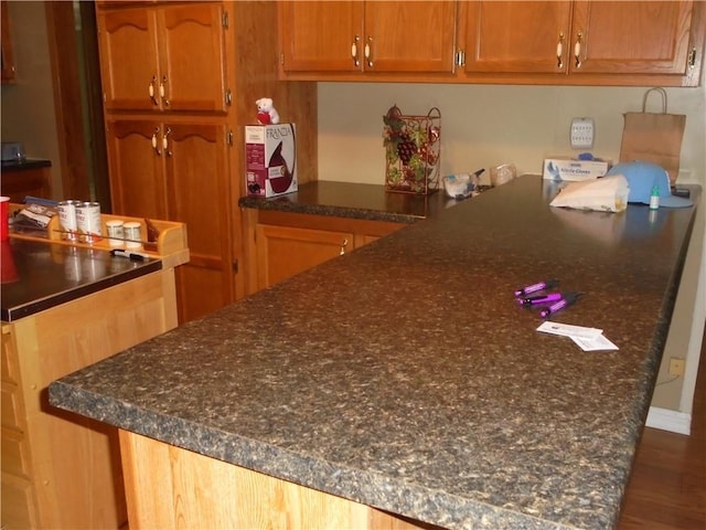 kitchen featuring dark hardwood / wood-style flooring and dark stone counters