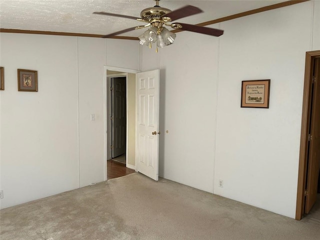 empty room featuring carpet, ceiling fan, ornamental molding, and a textured ceiling