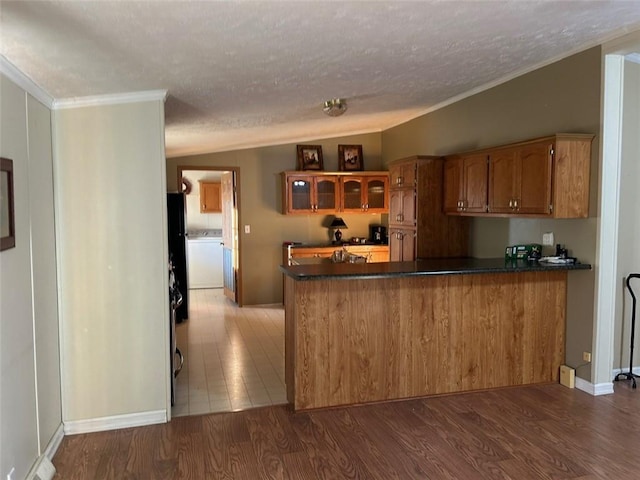 kitchen with kitchen peninsula, ornamental molding, a textured ceiling, vaulted ceiling, and hardwood / wood-style floors