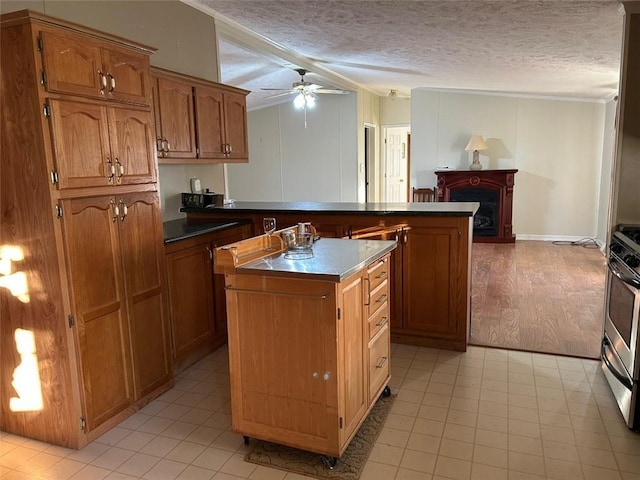 kitchen with ceiling fan, a kitchen island, a textured ceiling, and stainless steel range with gas stovetop