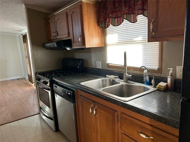 kitchen with appliances with stainless steel finishes, light wood-type flooring, a textured ceiling, crown molding, and sink