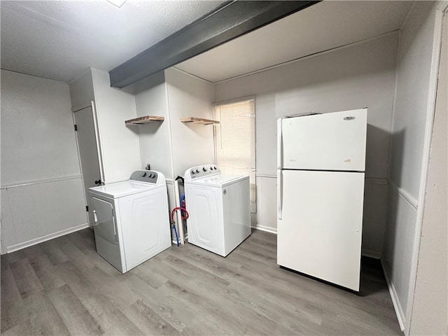 laundry room with washing machine and clothes dryer and light hardwood / wood-style flooring