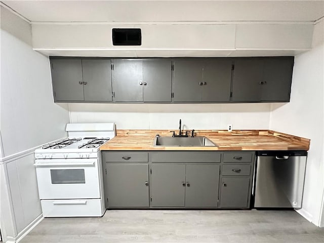 kitchen with gray cabinetry, sink, stainless steel dishwasher, white gas range, and light wood-type flooring