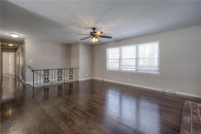 empty room featuring dark hardwood / wood-style flooring, ceiling fan, and a textured ceiling