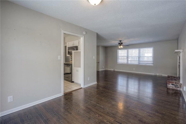 unfurnished living room with hardwood / wood-style flooring, ceiling fan, a brick fireplace, and a textured ceiling