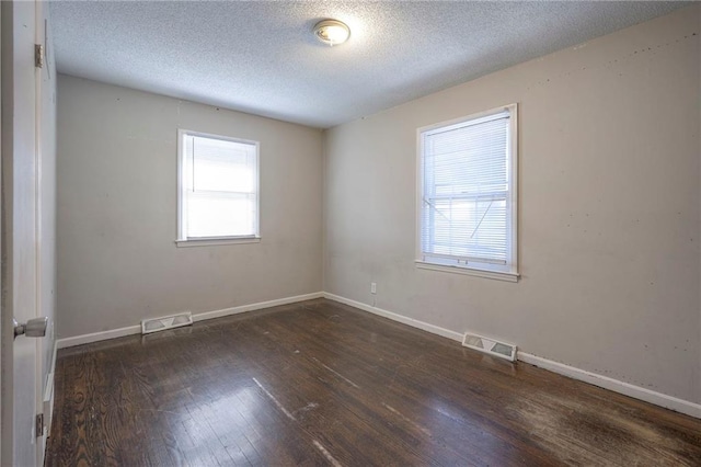 spare room with a wealth of natural light, dark hardwood / wood-style floors, and a textured ceiling