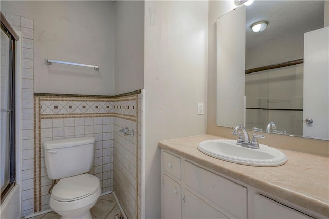 full bathroom featuring tile walls, shower / bath combination with glass door, tile patterned flooring, vanity, and toilet