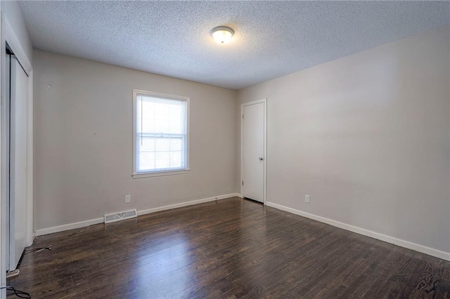 unfurnished bedroom with dark hardwood / wood-style floors, a textured ceiling, and a closet