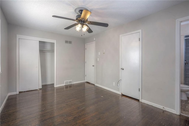 unfurnished bedroom featuring ceiling fan, ensuite bath, and dark hardwood / wood-style floors