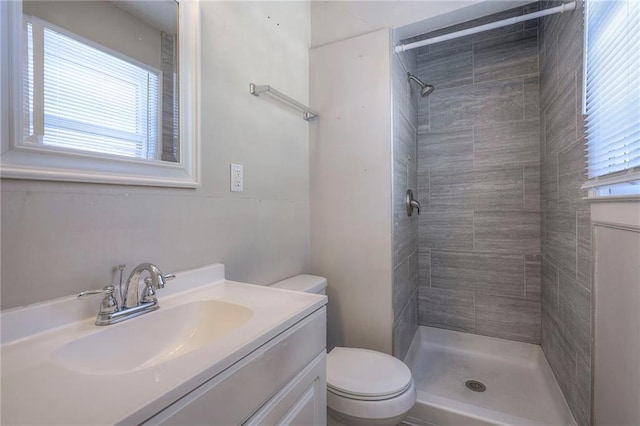 bathroom with a tile shower, vanity, and toilet