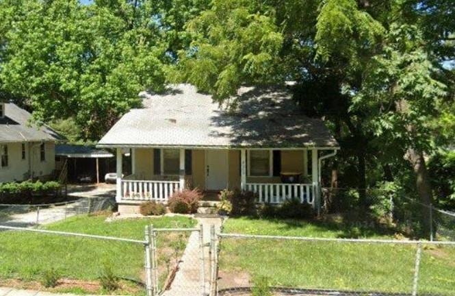 bungalow-style home featuring covered porch and a front yard