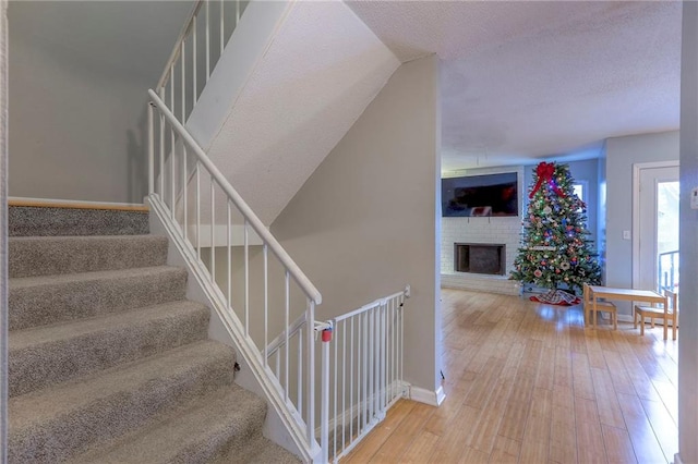 staircase featuring a fireplace and wood-type flooring