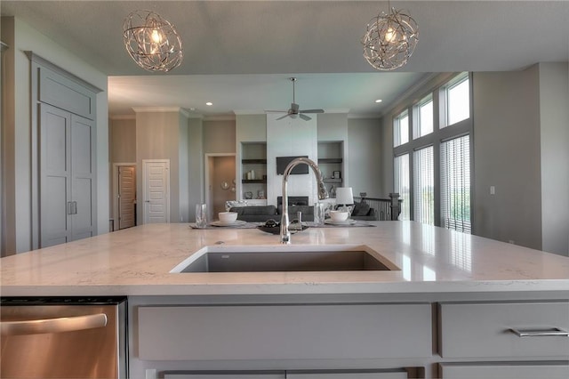 kitchen with a kitchen island with sink, sink, decorative light fixtures, and light stone countertops