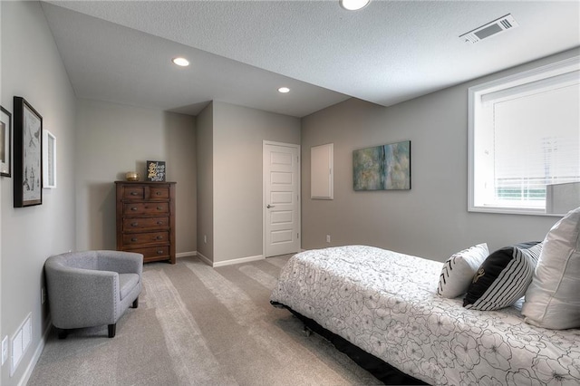 bedroom featuring light colored carpet and a textured ceiling