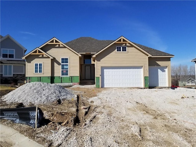 view of front of home featuring roof with shingles, driveway, and an attached garage