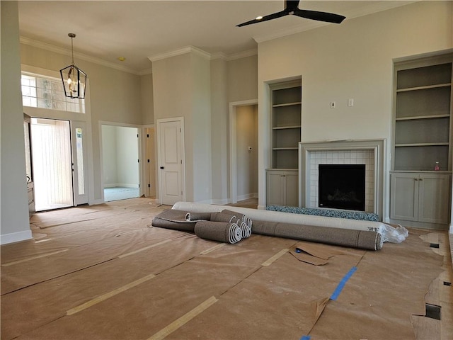 14608 Aspen Cir, Basehor, KS 66007 - unfurnished living room featuring crown molding, a ceiling fan, built in features, baseboards, and a tiled fireplace