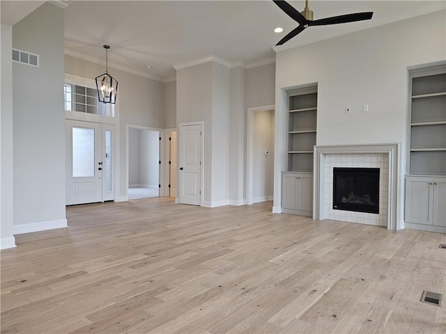 14608 Aspen Cir, Basehor, KS 66007 - unfurnished living room featuring ceiling fan, a chandelier, ornamental molding, a high ceiling, and built in shelves
