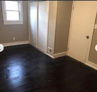 unfurnished bedroom with dark wood-type flooring