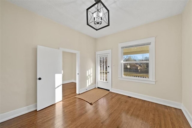 entrance foyer with hardwood / wood-style flooring, a textured ceiling, and a notable chandelier