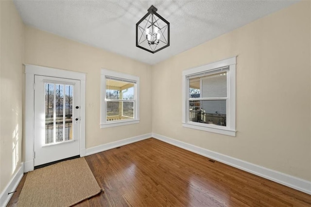 doorway featuring a textured ceiling, dark hardwood / wood-style flooring, and an inviting chandelier