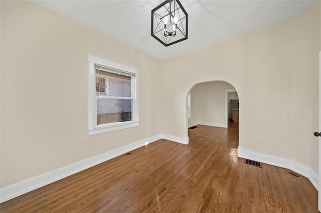 spare room featuring hardwood / wood-style floors and a notable chandelier