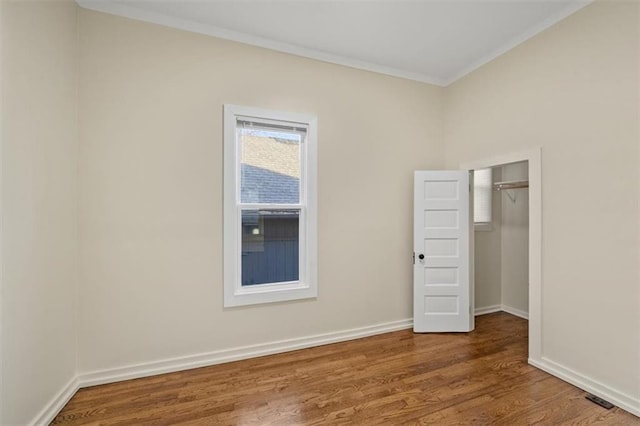 unfurnished bedroom with crown molding, a closet, and wood-type flooring