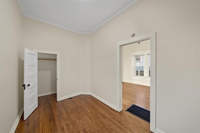 unfurnished bedroom featuring a closet, hardwood / wood-style floors, and crown molding