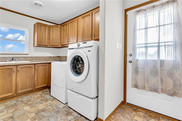 laundry room featuring crown molding, washer and dryer, sink, and cabinets