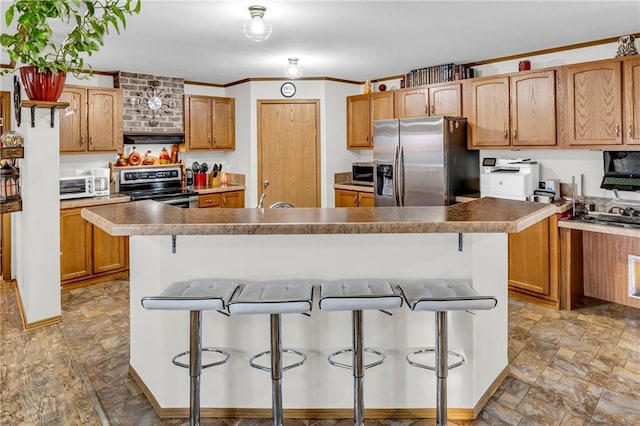 kitchen with crown molding, a breakfast bar area, a kitchen island, stainless steel appliances, and extractor fan