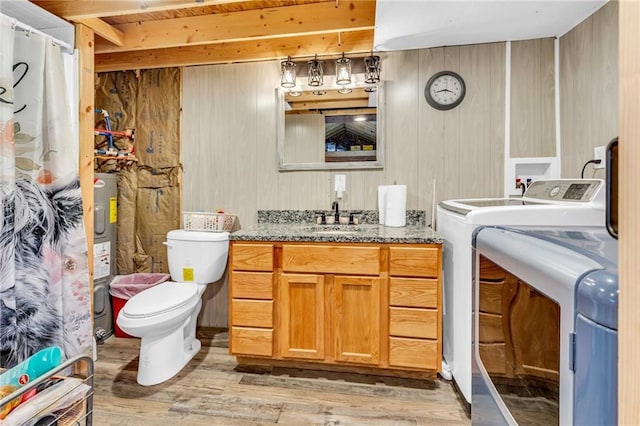 bathroom featuring vanity, wood walls, washer / dryer, and wood-type flooring