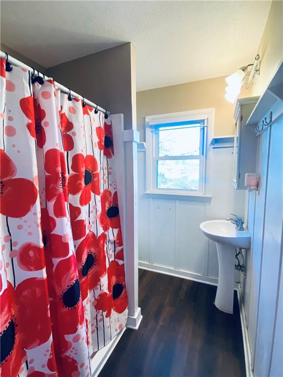 bathroom featuring sink, wood-type flooring, a textured ceiling, and walk in shower