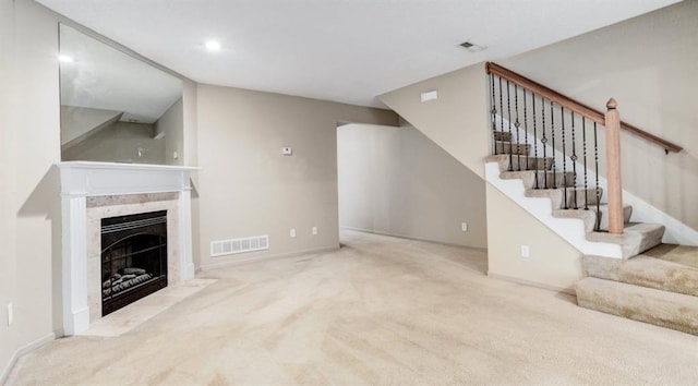 unfurnished living room with light carpet and a tiled fireplace