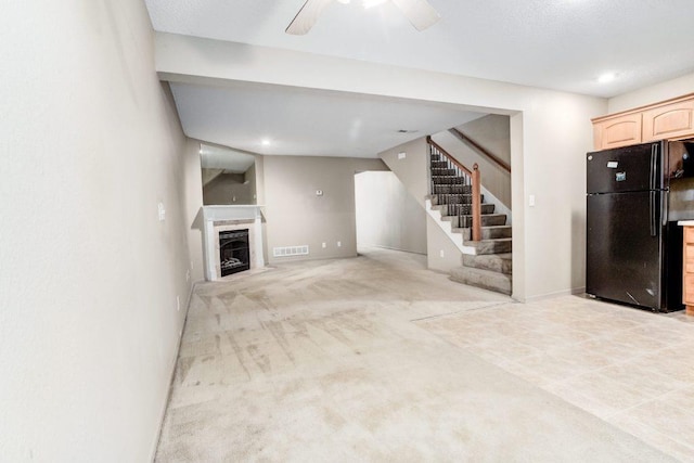 unfurnished living room featuring light carpet and ceiling fan