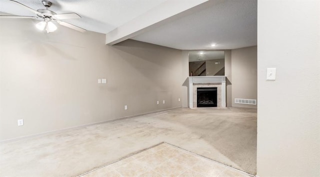 unfurnished living room featuring carpet flooring, ceiling fan, beamed ceiling, and a textured ceiling