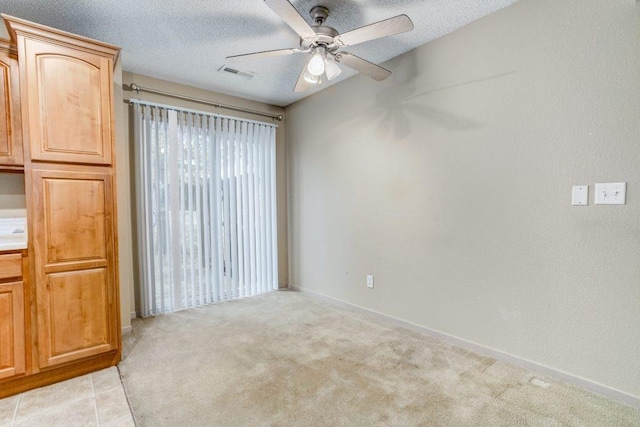 carpeted spare room featuring ceiling fan and a textured ceiling