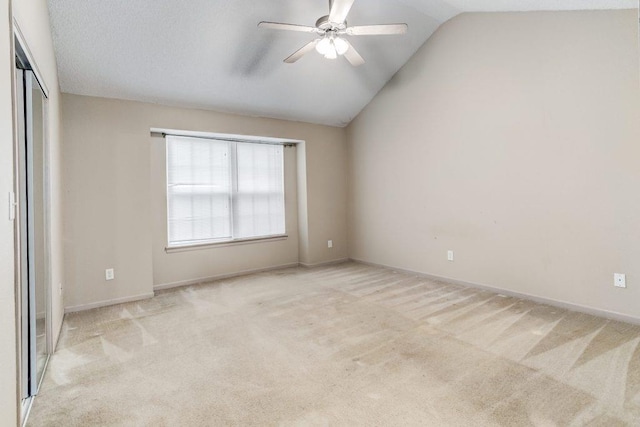 empty room featuring ceiling fan, light colored carpet, and vaulted ceiling