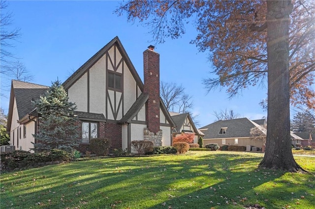 exterior space with a chimney, stucco siding, a lawn, and roof with shingles