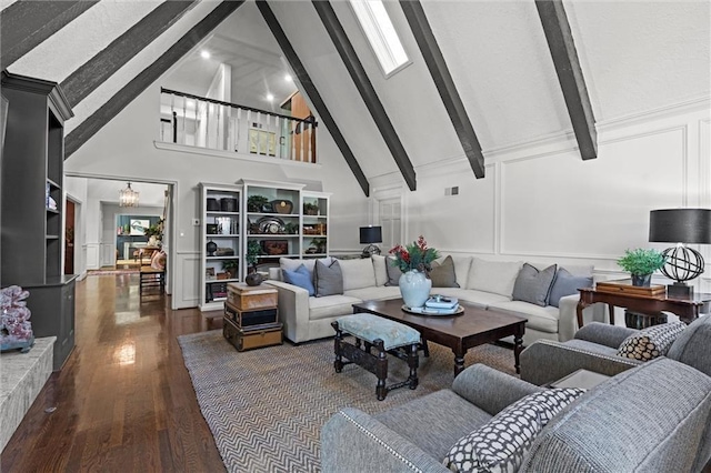 living room featuring beam ceiling, a decorative wall, a notable chandelier, and wood finished floors