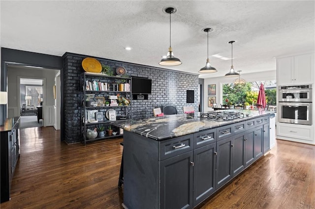 kitchen featuring dark wood finished floors, dark stone countertops, appliances with stainless steel finishes, white cabinets, and a textured ceiling