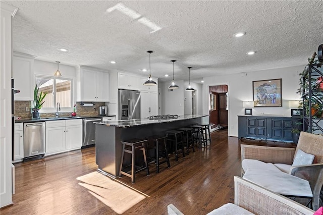 kitchen with a breakfast bar area, dark wood-style floors, appliances with stainless steel finishes, open floor plan, and a center island