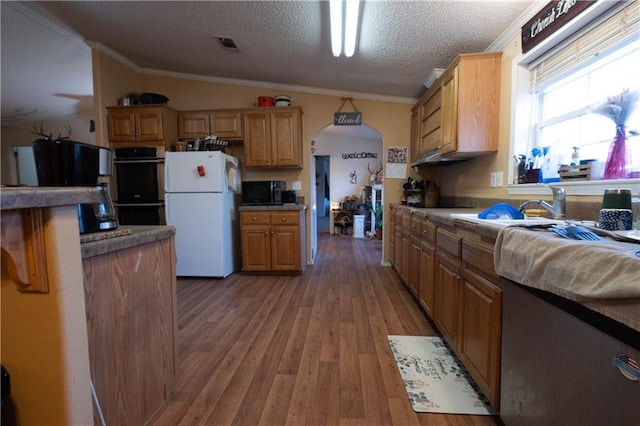 kitchen featuring black appliances, vaulted ceiling, hardwood / wood-style flooring, ornamental molding, and a textured ceiling