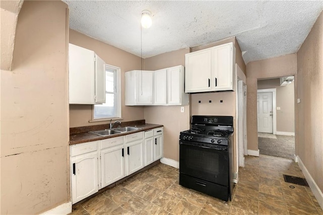 kitchen featuring a textured ceiling, white cabinets, black gas stove, and sink