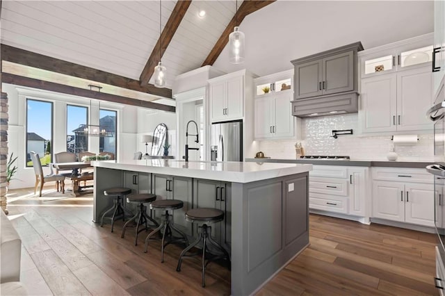 kitchen featuring a center island with sink, a breakfast bar, stainless steel fridge, and dark hardwood / wood-style flooring