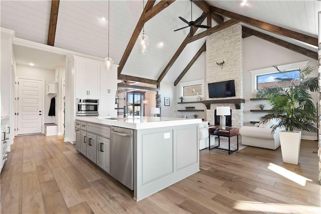 kitchen featuring appliances with stainless steel finishes, light wood-type flooring, high vaulted ceiling, and an island with sink