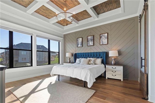 bedroom with beamed ceiling, a barn door, hardwood / wood-style flooring, and coffered ceiling